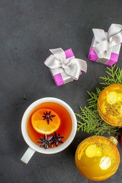 Vista vertical de regalos una taza de té negro y accesorios de decoración sobre fondo negro