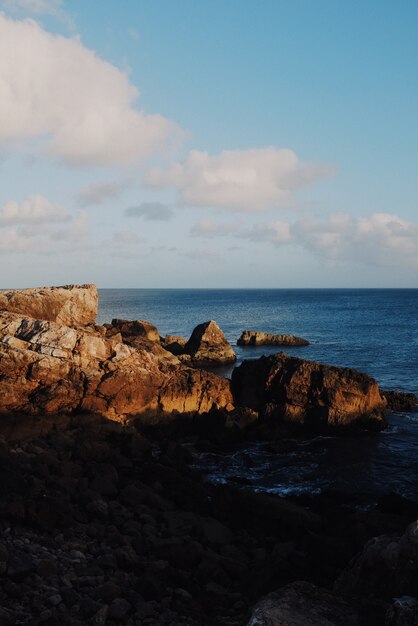 Vista vertical de rocas al amanecer con el océano de fondo