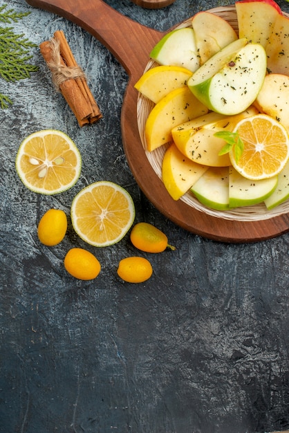 Foto gratuita vista vertical de rodajas de manzana fresca en un plato blanco con limón sobre tabla de cortar de madera en el lado derecho sobre fondo gris