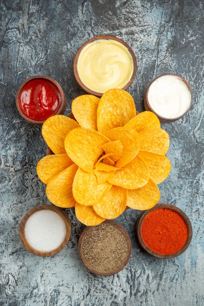 Vista vertical de sabrosas patatas fritas decoradas en forma de flor y sal con mayonesa de salsa de tomate sobre fondo gris