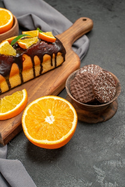 Vista vertical de suaves y sabrosos pasteles cortan limones con galletas en la tabla de cortar de madera