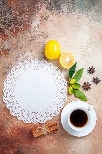 Vista vertical de una taza de té, té negro, servilleta de limón y té en coloridos