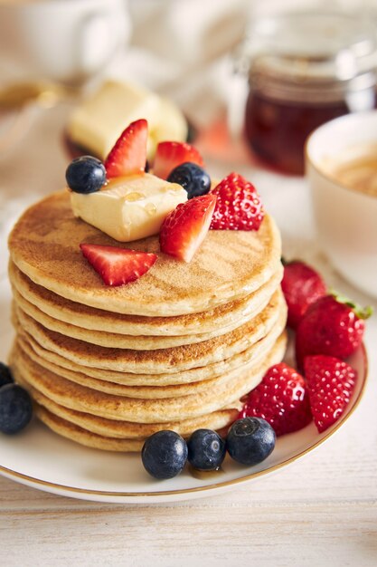 Vista vertical de tortitas de tofu vegano con frutas en una placa blanca.