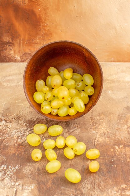 Foto gratuita vista vertical de uvas amarillas frescas caídas de una olla pequeña