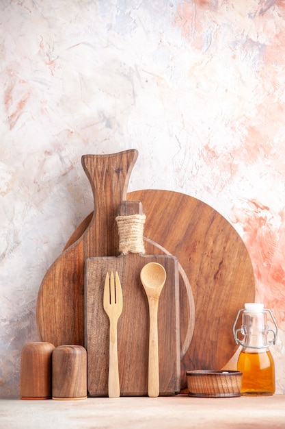 Foto gratuita vista vertical de varias tablas de cortar cucharas de madera botella de aceite pequeña en superficie colorida