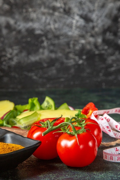 Vista vertical de verduras frescas cortadas enteras y especias del medidor en la superficie de colores mezclados con espacio libre