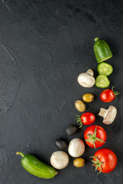 Vista vertical de verduras frescas enteras y cortadas setas crudas sobre superficie negra