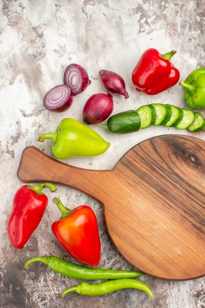 Vista vertical de las verduras frescas necesarias para la preparación de la cena alrededor de la tabla de cortar de madera