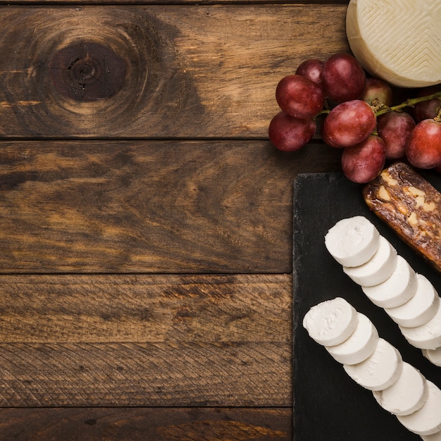 Vivid queso y uvas rojas sobre superficie de madera sucia