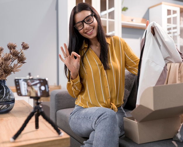 Vlogger en casa desembalaje de ropa con smartphone