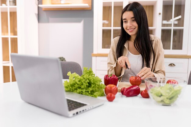 Vlogger femenina en casa grabando video con laptop