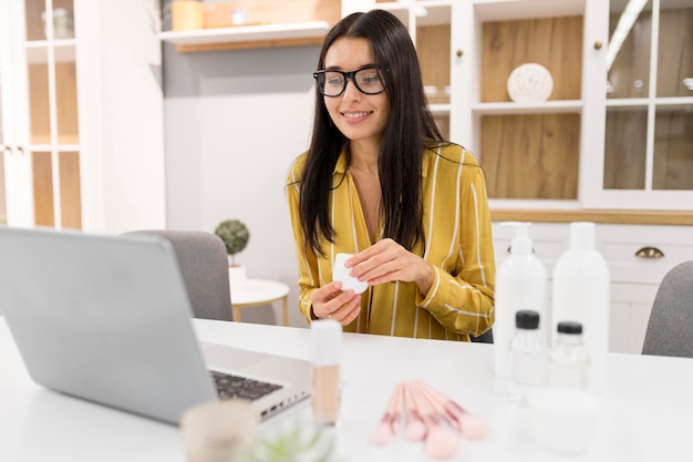 Vlogger femenina en casa con laptop y productos