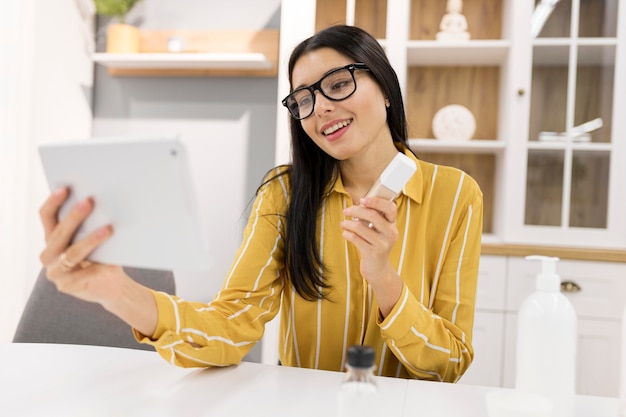 Foto gratuita vlogger femenina en casa con producto y tableta