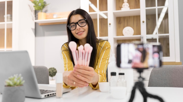 Foto gratuito vlogger femenina en casa con smartphone y pinceles