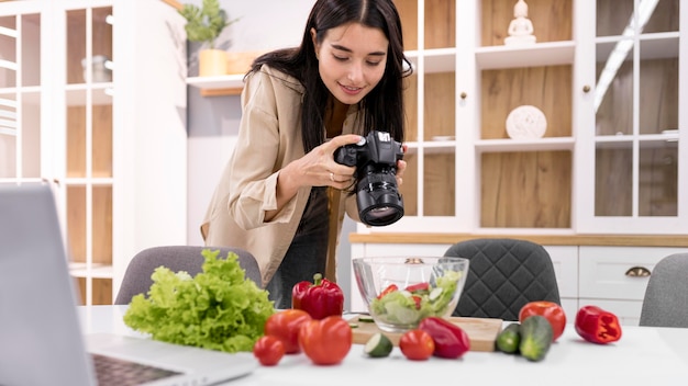 Vlogger femenina en casa tomando fotografías con cámara