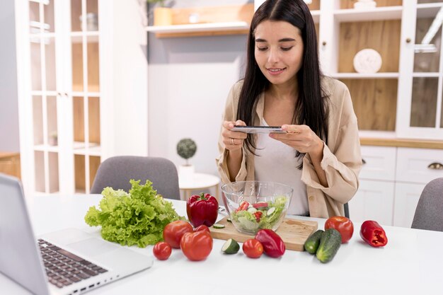 Vlogger femenina grabando video con laptop y smartphone