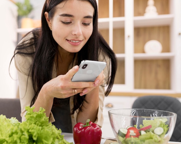 Vlogger femenina tomando fotografías en casa con smartphone