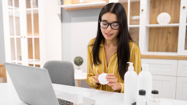 Vlogger femenino en casa con laptop y botellas