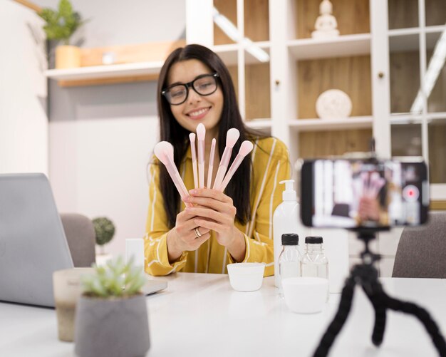 Vlogger femenino en casa con laptop y cepillos