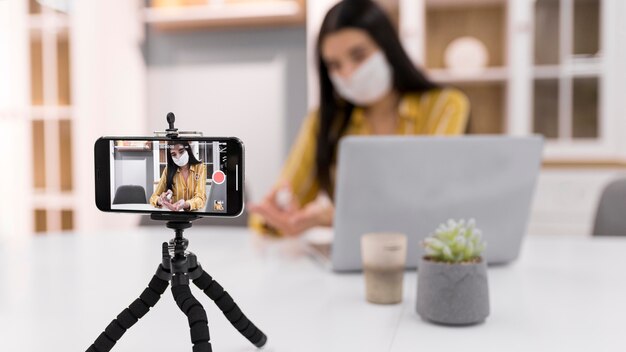 Vlogger femenino en casa con laptop y smartphone