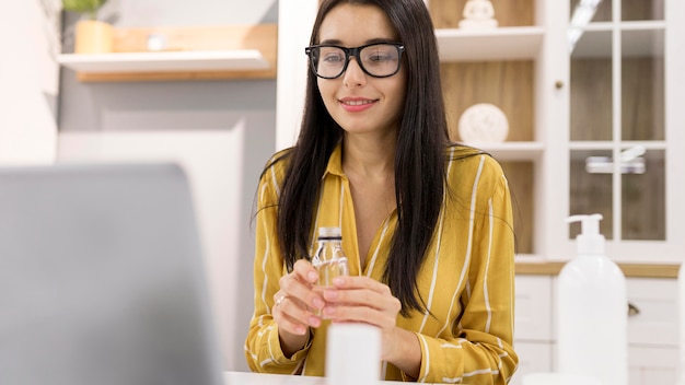 Vlogger femenino en casa con producto y portátil