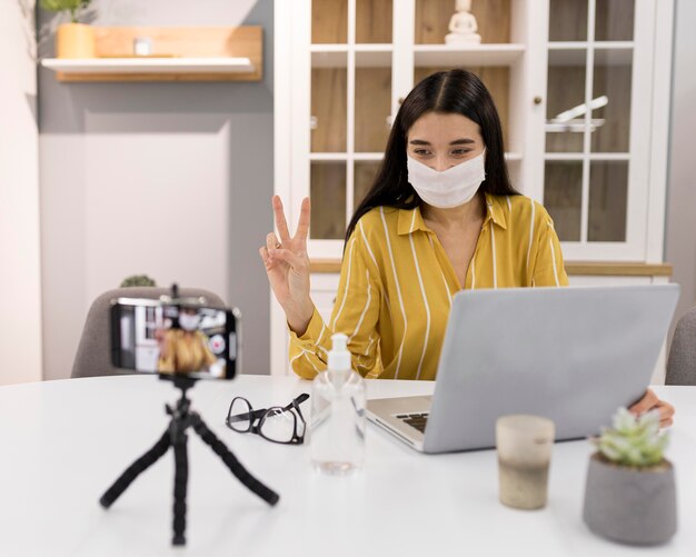 Vlogger femenino en casa con smartphone y portátil