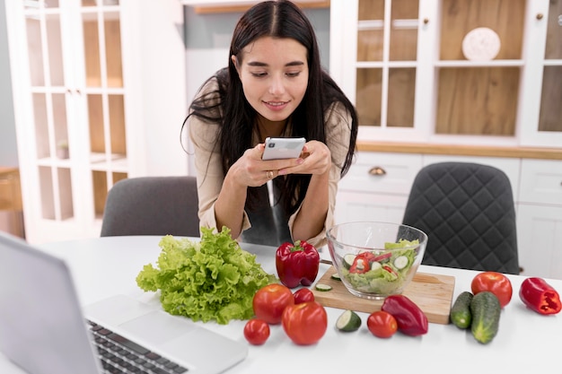 Foto gratuita vlogger femenino tomando fotografías con smartphone