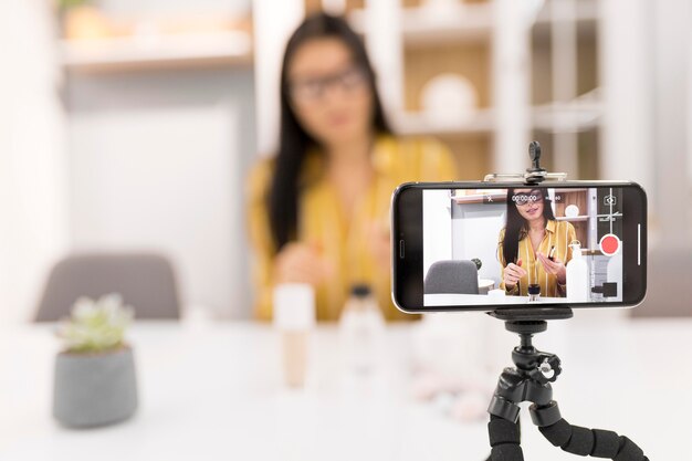 Vlogger mujer Defocused en casa con smartphone