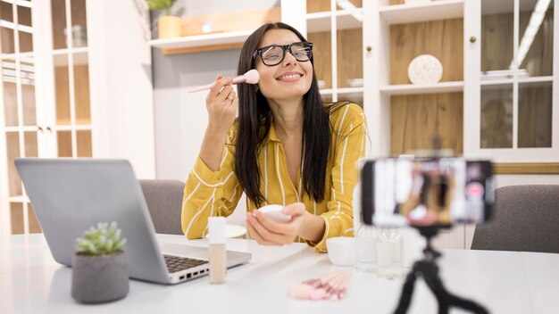 Vlogger mujer sonriente en casa con smartphone y cepillo