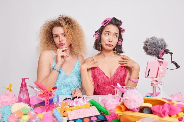 Foto gratuita las vlogueras de interior usan ropa festiva rodeadas de productos de belleza, se preparan para la cita, hacen video en vivo, hablan con los suscriptores, hacen una reseña de podast en las redes sociales. marketing de influencers