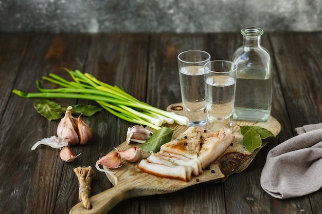 Vodka con manteca de cerdo y cebolla verde sobre mesa de madera.