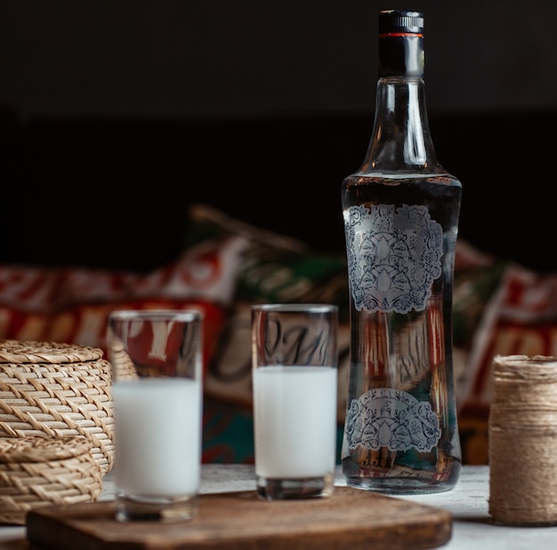 Vodka turco raki en vasos con una botella a un lado.