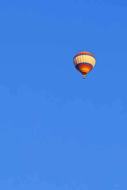 Volando en globo multicolor en el cielo azul brillante