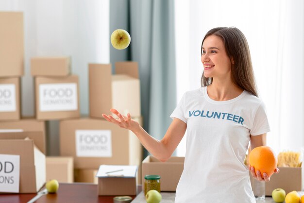 Voluntaria feliz jugando con comida para donación