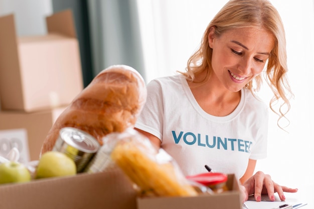 Foto gratuita voluntaria sonriente ayudando con donaciones de alimentos