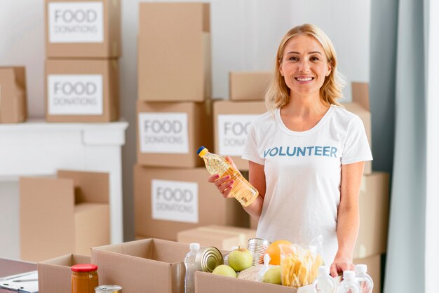 Voluntaria sonriente preparando caja con comida para donación