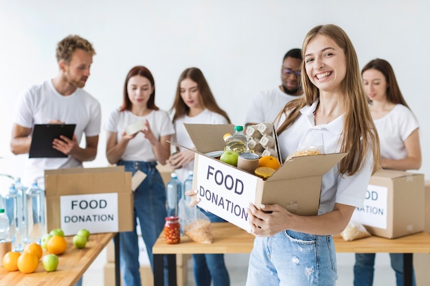 Voluntaria sonriente sosteniendo donaciones de alimentos