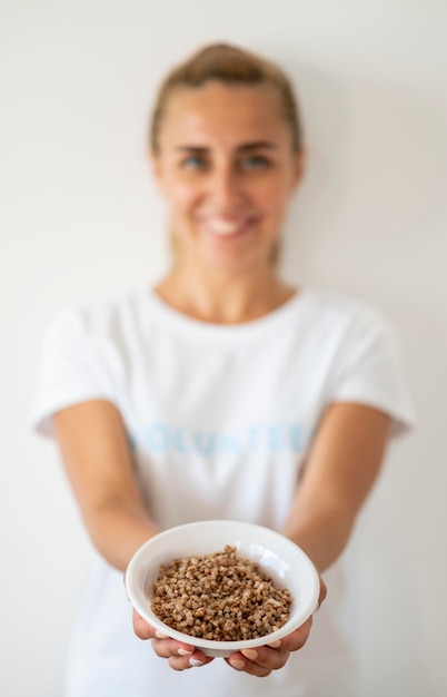 Foto gratuita voluntaria sonriente sosteniendo un plato de comida donada