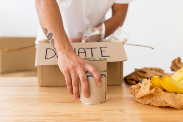Voluntario colocando latas con comida en primer plano de cajas