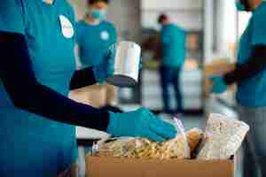 Foto gratuita voluntario irreconocible empacando comida donada en caja de cartón