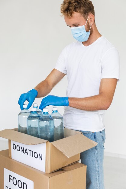 Voluntario masculino preparando botellas de agua para donación