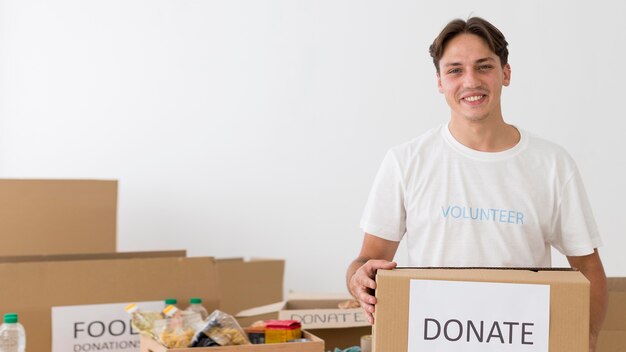 Voluntario sonriente sosteniendo una caja de donación con espacio de copia