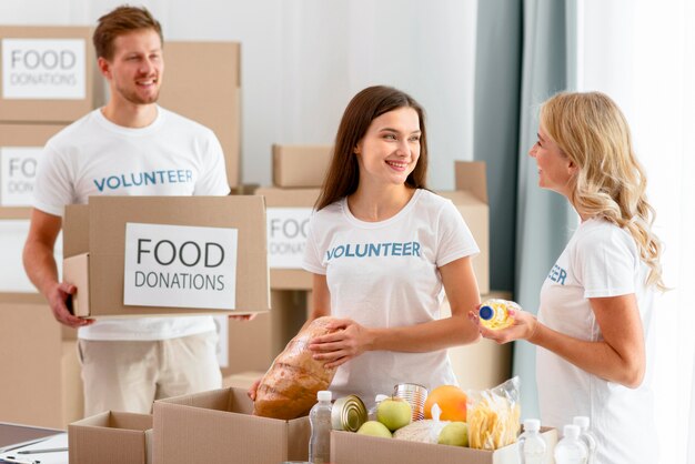 Voluntarios alegres preparando provisiones de alimentos para donaciones
