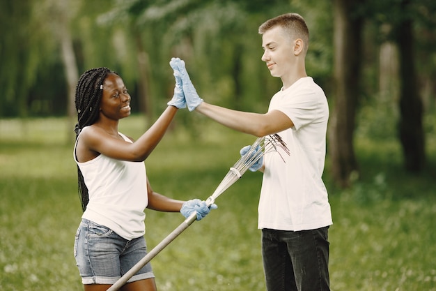 Voluntarios felices chocando los cinco entre sí después de completar las tareas. Niña afroamericana y niño europeo.