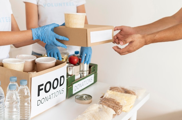 Voluntarios con guantes entregando cajas con provisiones para donación