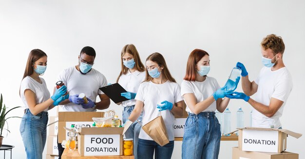 Voluntarios con guantes y máscaras médicas preparando caja para donación