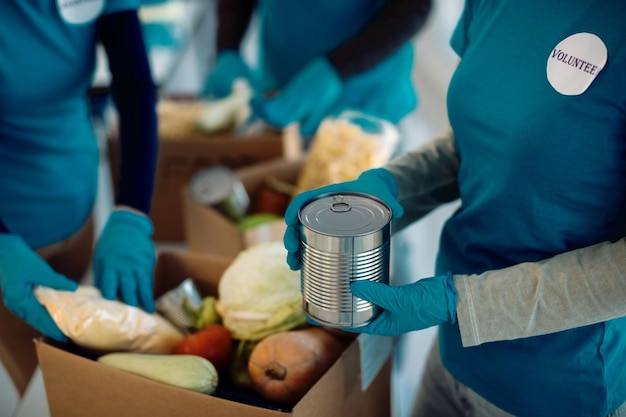 Voluntarios irreconocibles empacando comida donada en cajas de cartón