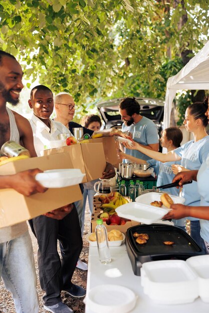 Los voluntarios proporcionan cajas de comida y productos enlatados a las personas necesitadas Los ancianos y las personas sin hogar reciben alimento de los trabajadores sonrientes que encarnan el espíritu de la campaña de alimentos y la organización sin fines de lucro