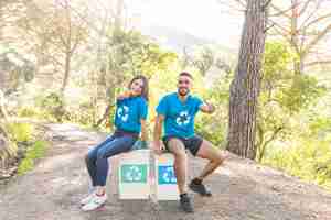 Foto gratuita voluntarios sentados en contenedores de basura en el bosque