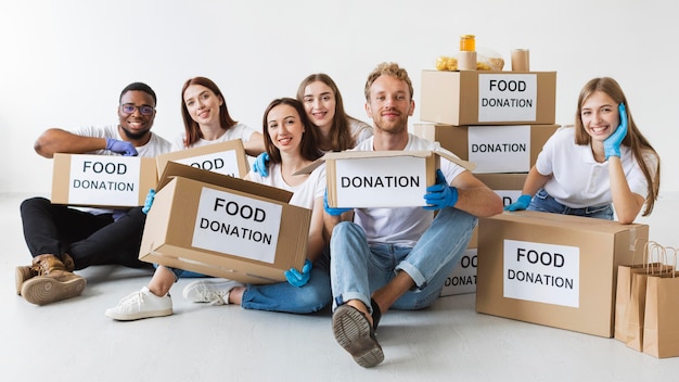 Voluntarios sonrientes posando junto con cajas de donación de alimentos